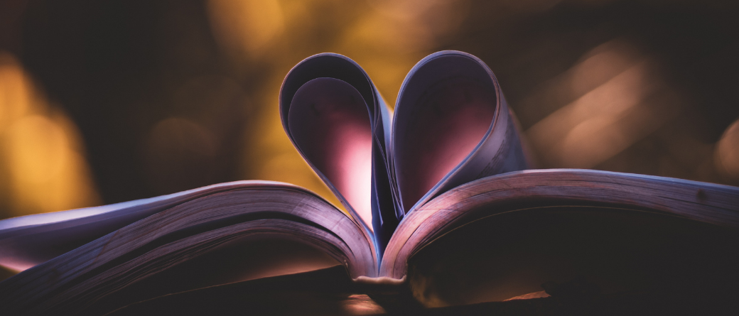 An image of book pages made into a heart shape, with a bokeh background